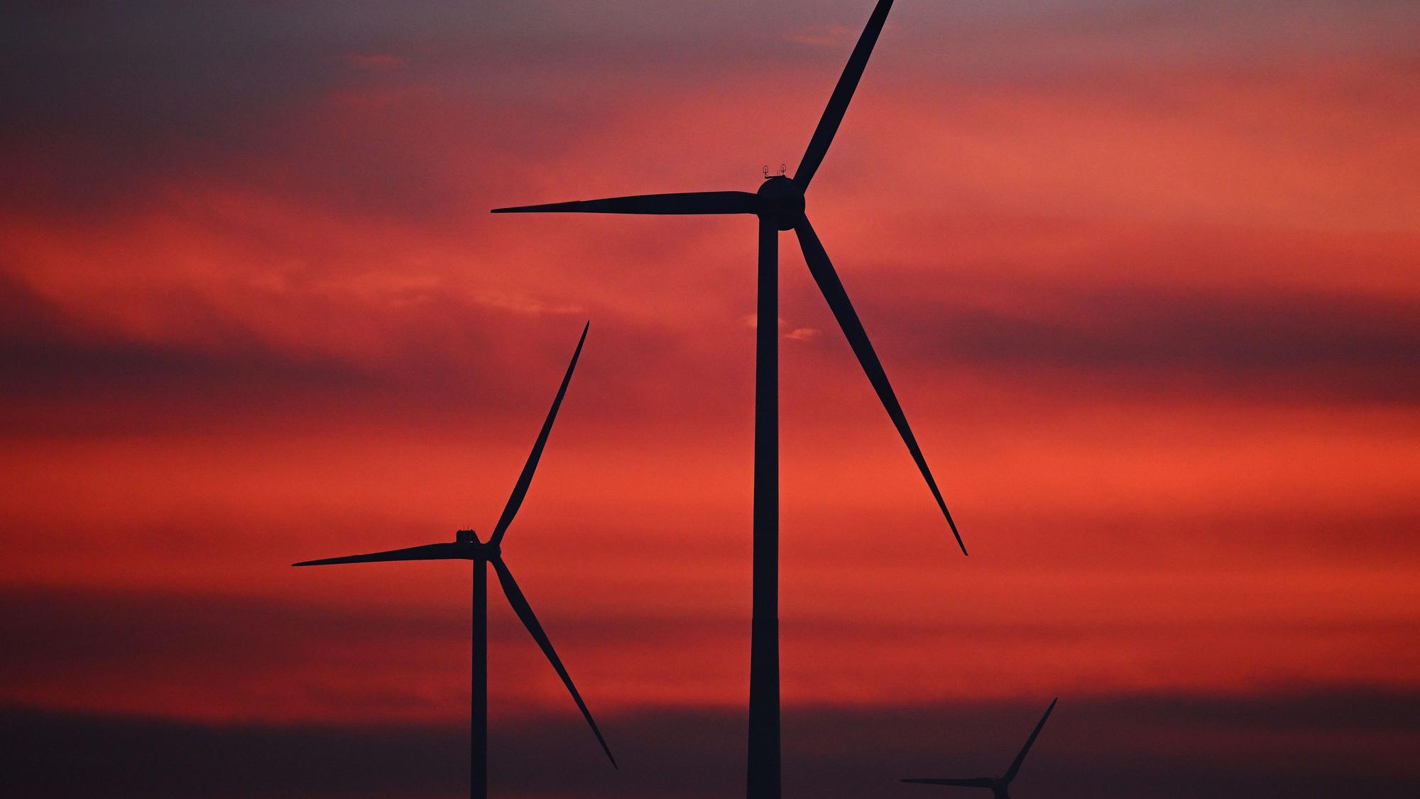 Diese Windräder in einem Windpark wurden bei Sonnenaufgang fotografiert. Diese Aufnahme ist ein Symbolfoto.