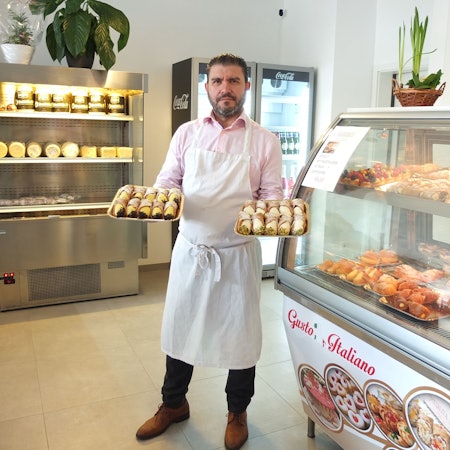 Francesco Bonfissuto mit süßen Spezialitäten in der Hand in seinem Geschäft.