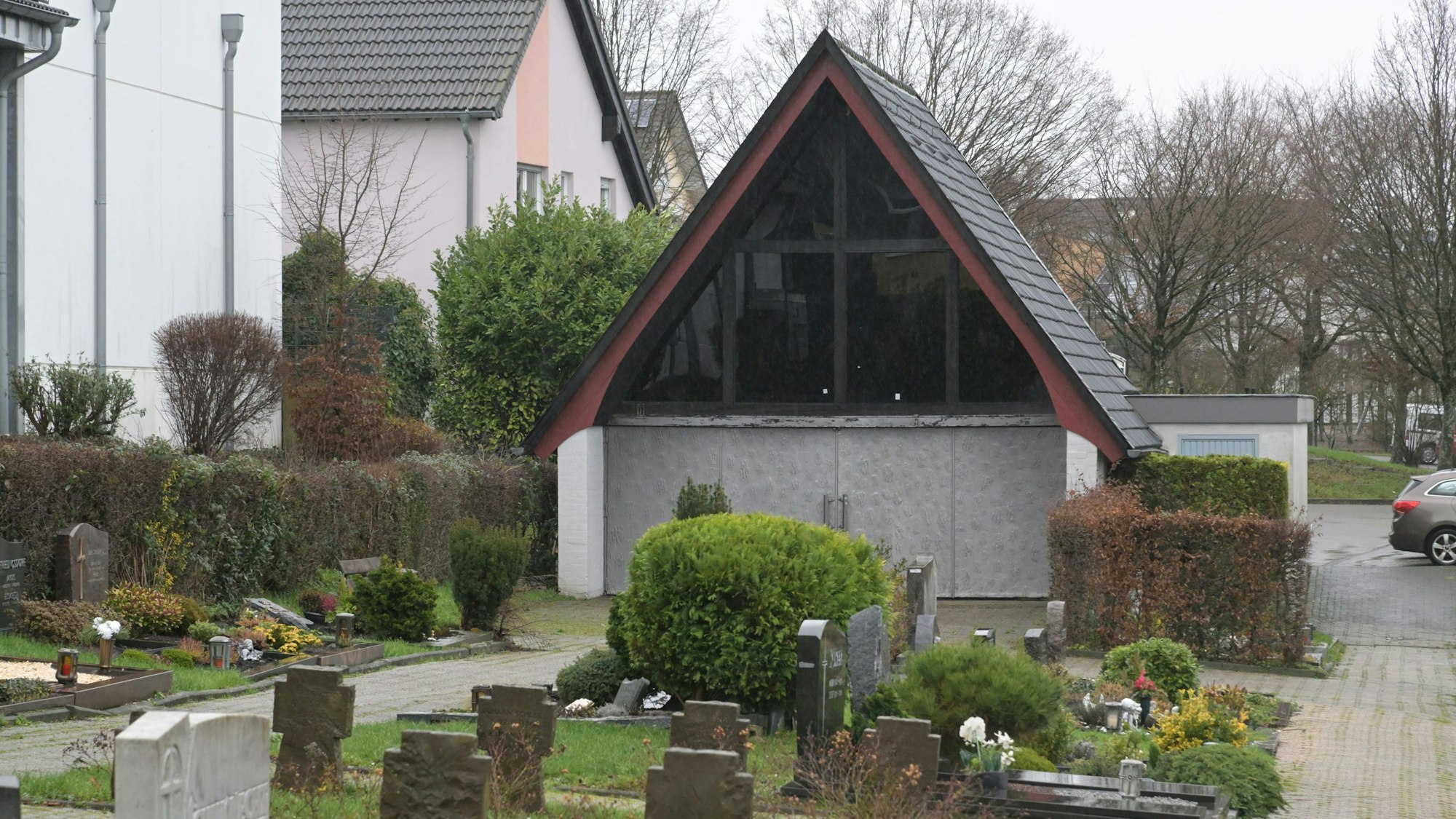 Die Trauerhalle auf dem Friedhof Bechen steht hinter Grabsteinen.