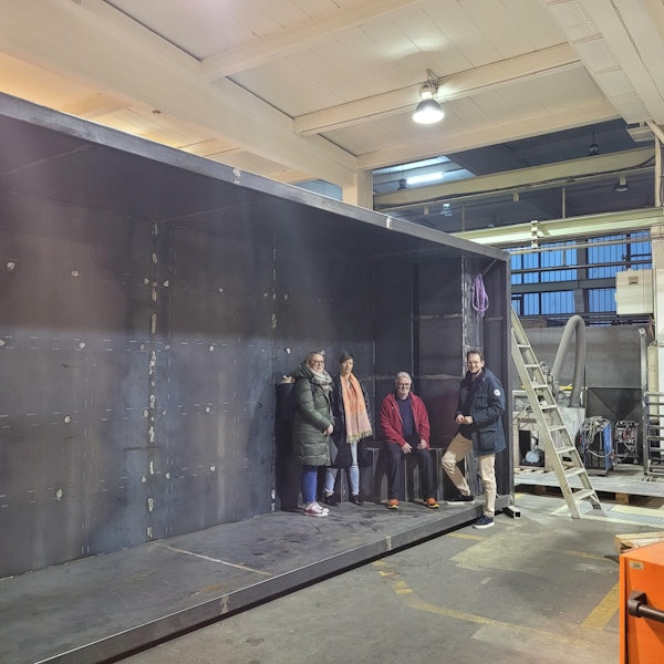 Vier Personen stehen und sitzen in einer dunklen Betonwanne, die auf der Seite liegt.