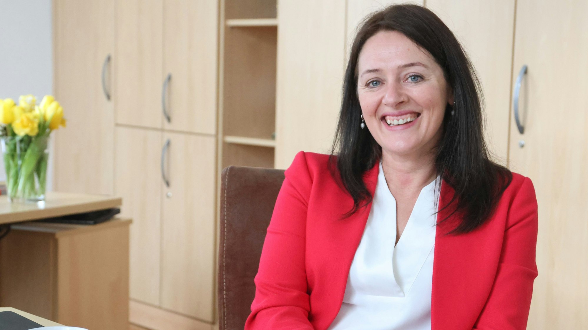 Bürgermeisterin Larissa Weber sitzt mit rotem Blazer bekleidet an ihrem Schreibtisch.
