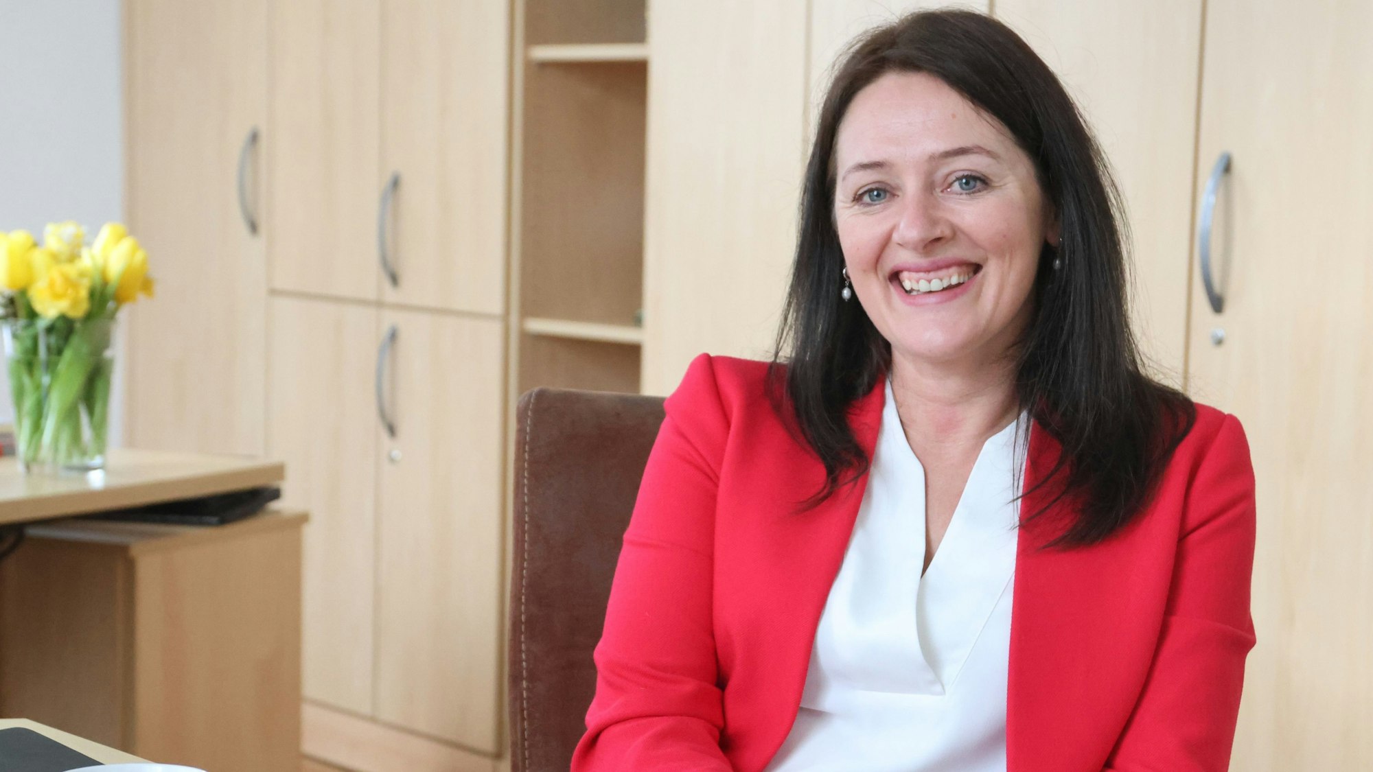 Bürgermeisterin Larissa Weber sitzt mit rotem Blazer bekleidet an ihrem Schreibtisch.