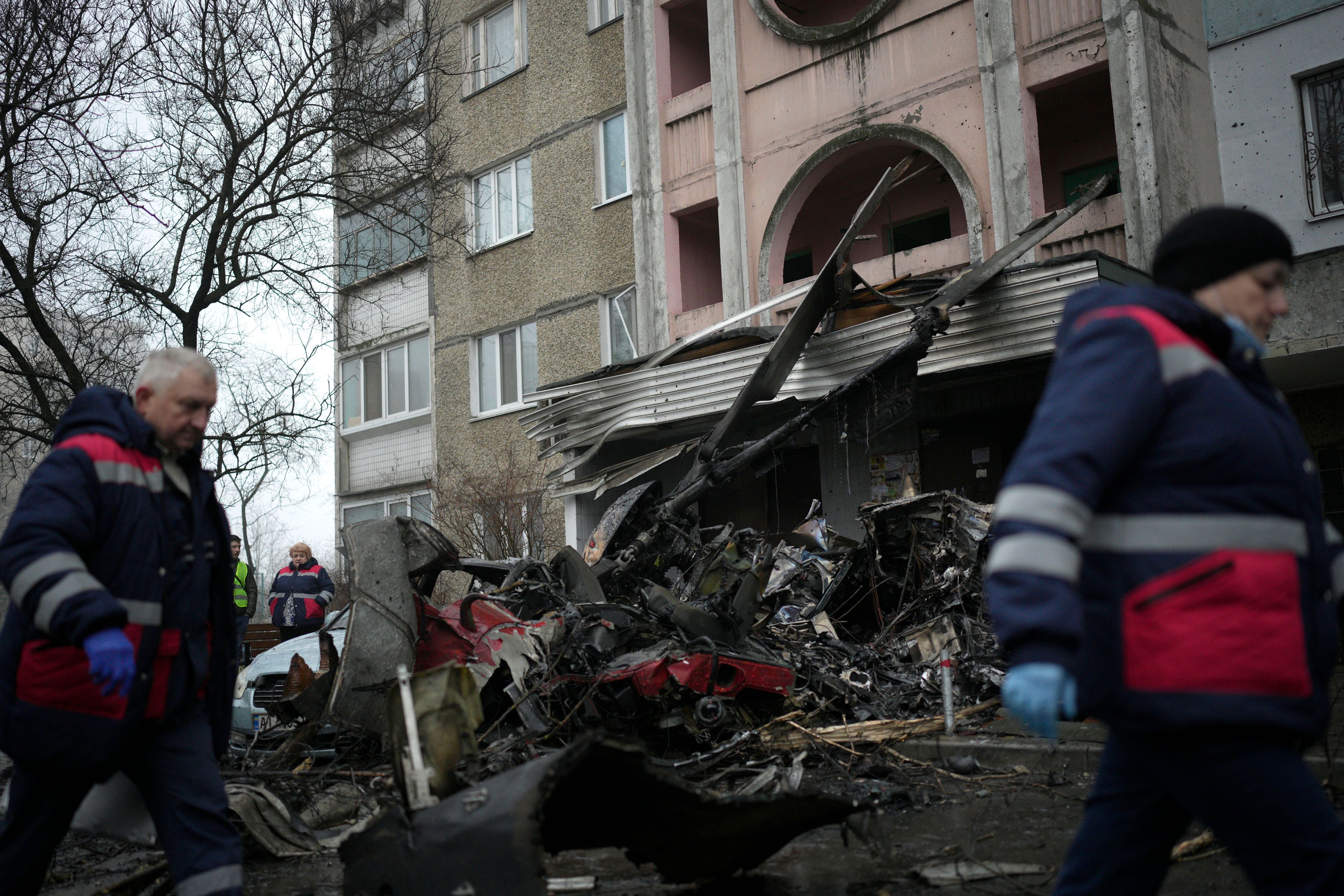 Arbeiter gehen an der Absturzstelle eines Hubschraubers auf zivile Infrastruktur in Brovary vorbei.
