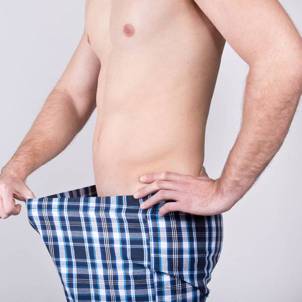 Ein Mann zieht die Unterhose nach vorne und blickt auf sein Geschlechtsteil.