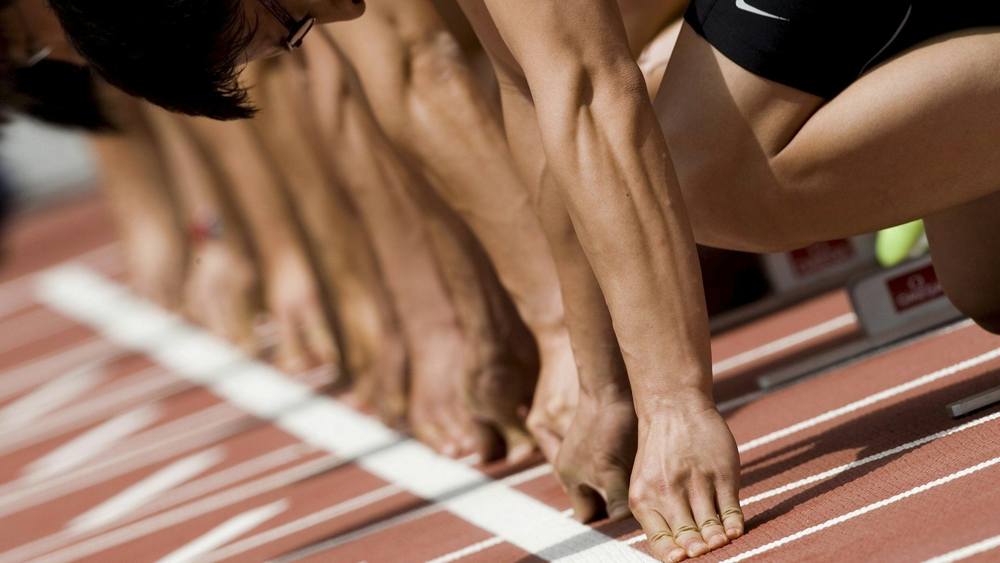 Athleten am Start eines 100 Meter Laufes.|