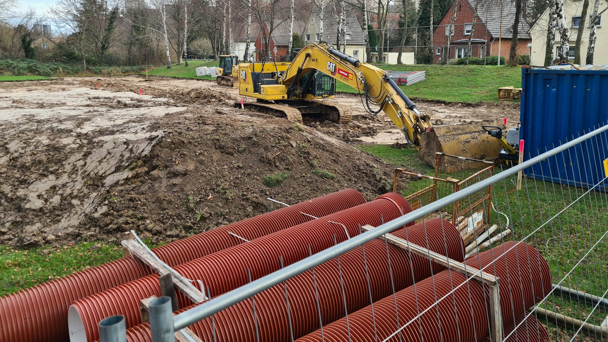Ein Bagger hebt Erde für den Aufbau der Wohncontainersiedlung für Flüchtlinge.