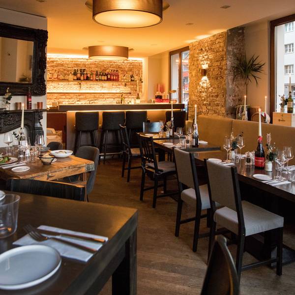 Innenraum des Restaurants Barile mit gedeckten, dunklen Holztischen