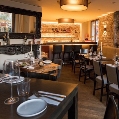 Innenraum des Restaurants Barile mit gedeckten, dunklen Holztischen