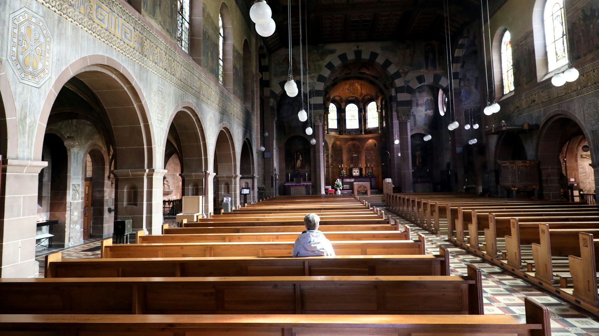 Eine Frau sitzt alleine in der Kirche St. Laurentius in Bergisch Gladbach.