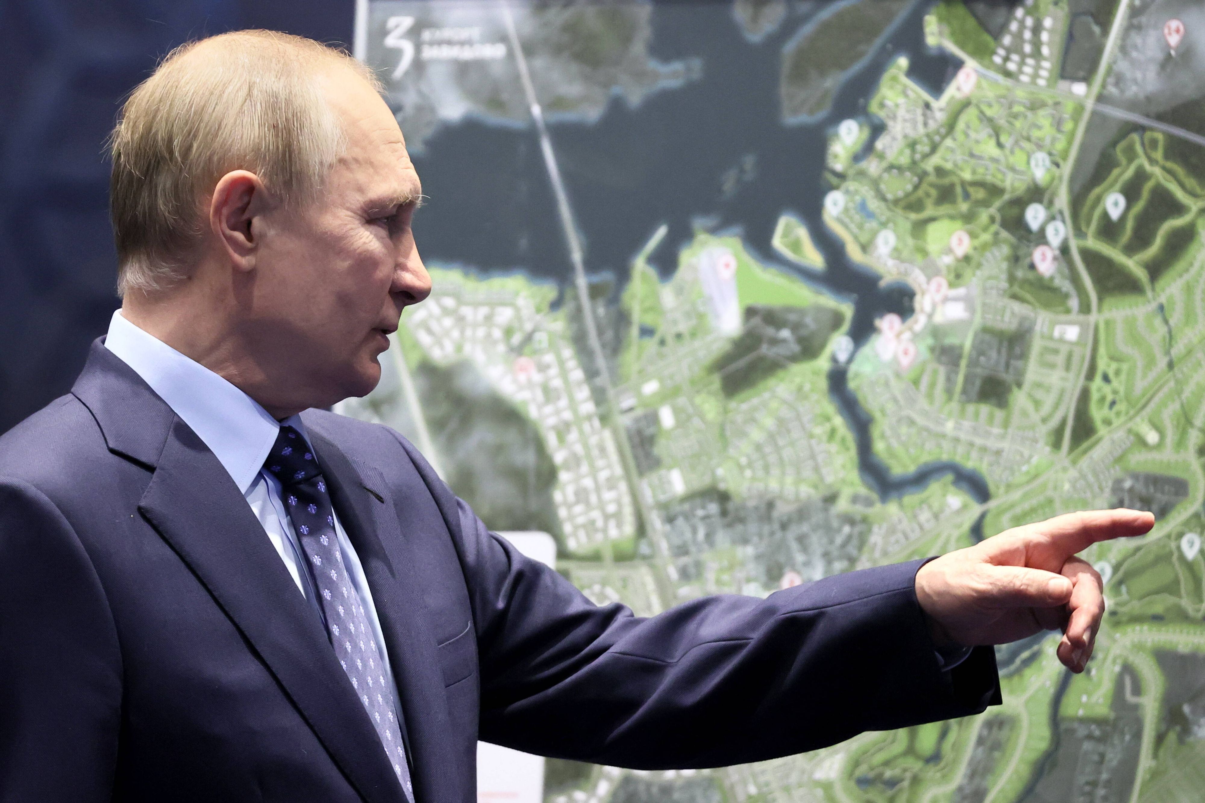 Wladimir Putin zeigt mit dem Finger auf eine Landkarte.
