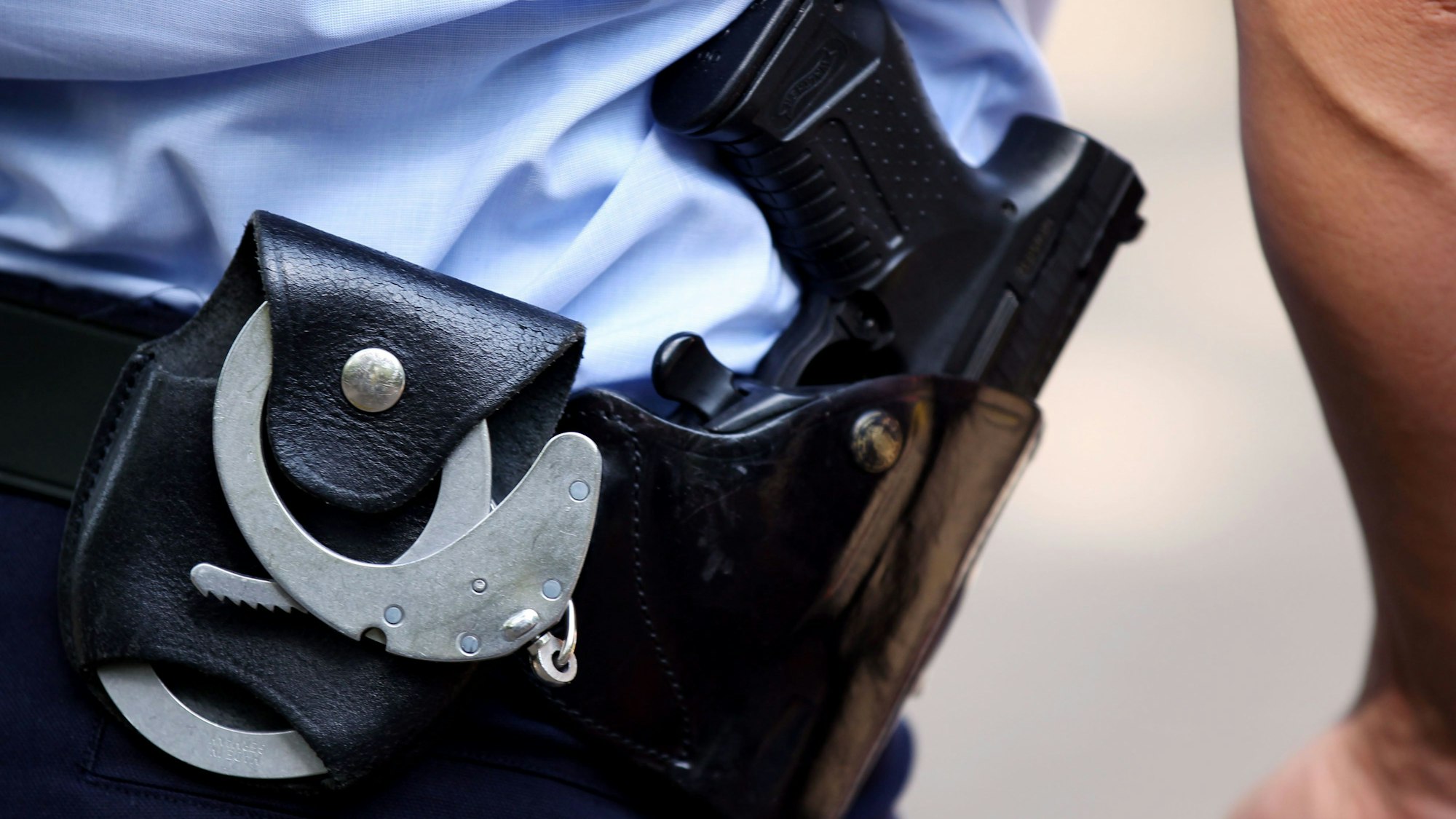 Ein NRW-Polizist trägt Handschellen und seine Dienstwaffe bei sich