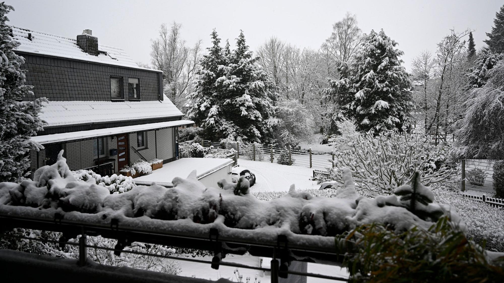 Geländer eines Balkons, Garten und Bäume sind mit Schnee bedeckt.