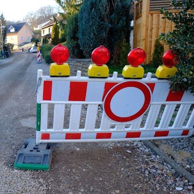 Auf der Baustelle im Höhenweg in Mechernich-Vussem ruhen aktuell die Bauarbeiten witterungsbedingt. Absperrbaken und die fehlende Teerdecke weisen darauf hin, dass die Straße ausgebaut wird.