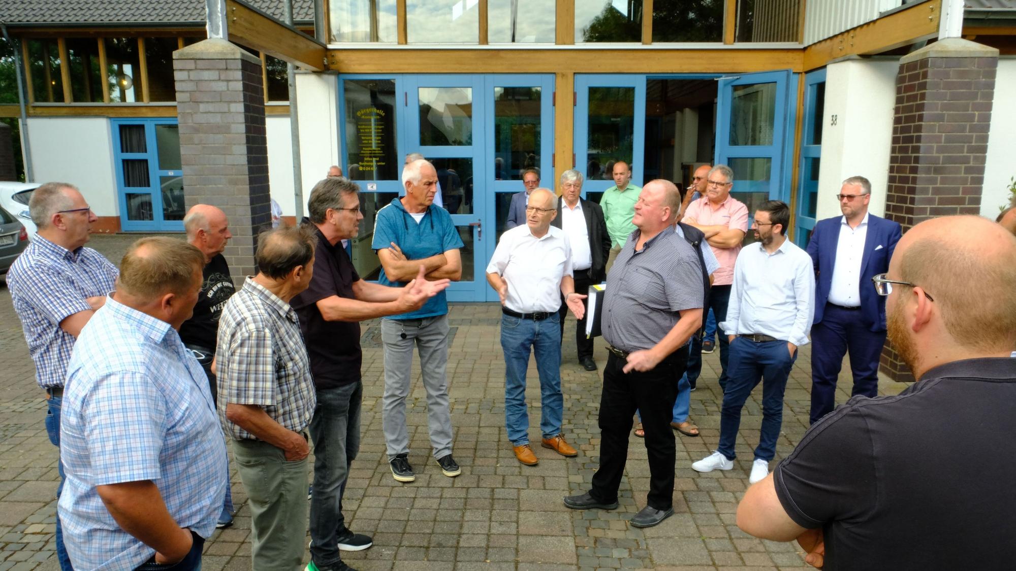 Nach der Ratssitzung in Kommern diskutieren Bürger im Halbrund vor der Tür mit Verwaltungsvertretern und Kommunalpolitikern über die rechtliche Bewertung ihrer Anliegerbeiträge.