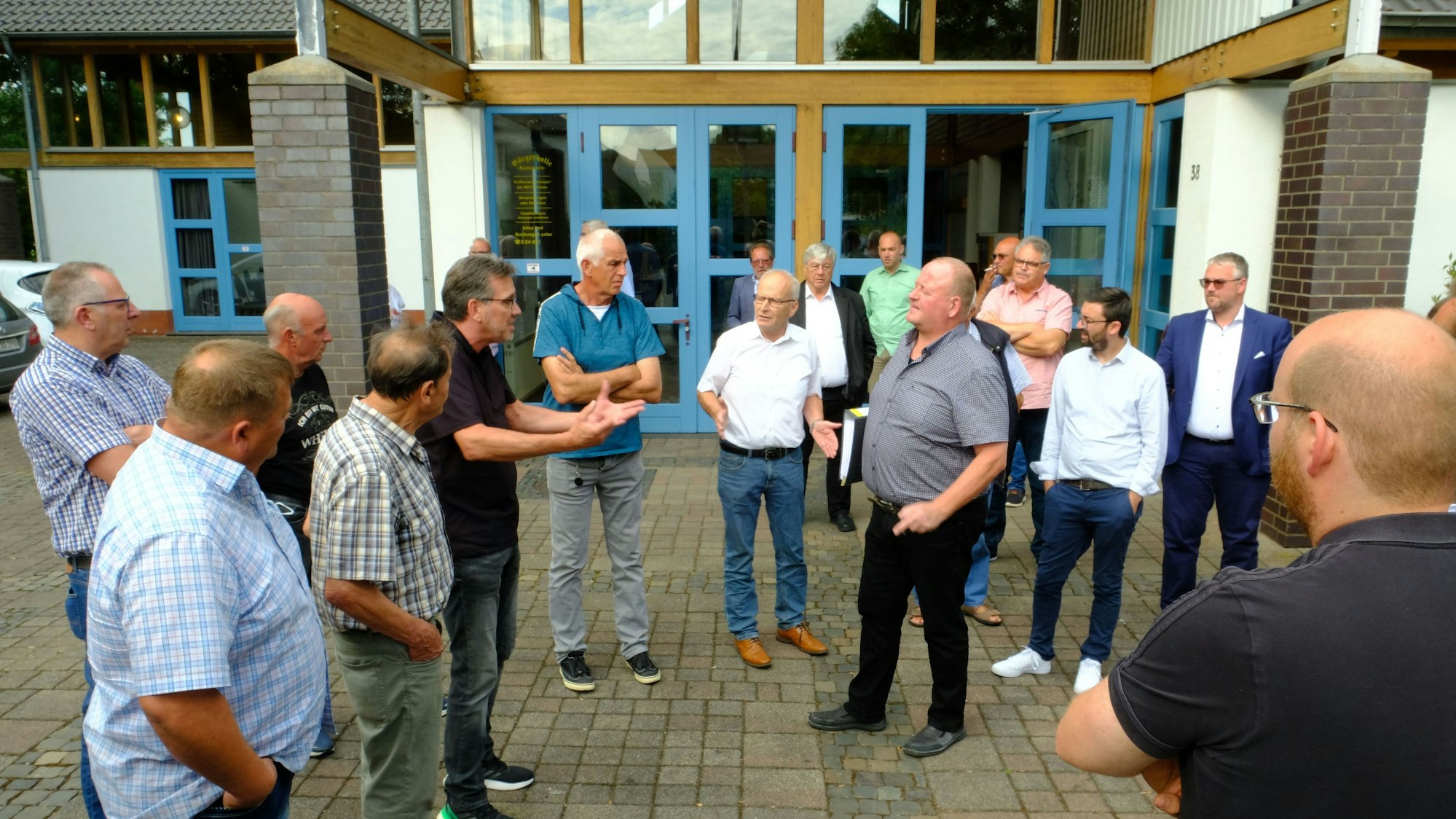 Nach der Ratssitzung in Kommern diskutieren Bürger im Halbrund vor der Tür mit Verwaltungsvertretern und Kommunalpolitikern über die rechtliche Bewertung ihrer Anliegerbeiträge.