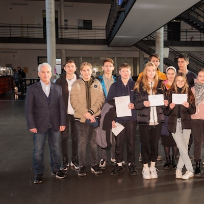 Schülerinnen, Schüler und Lehrer stehen zusammen, einige halten ein Diplom vor sich.