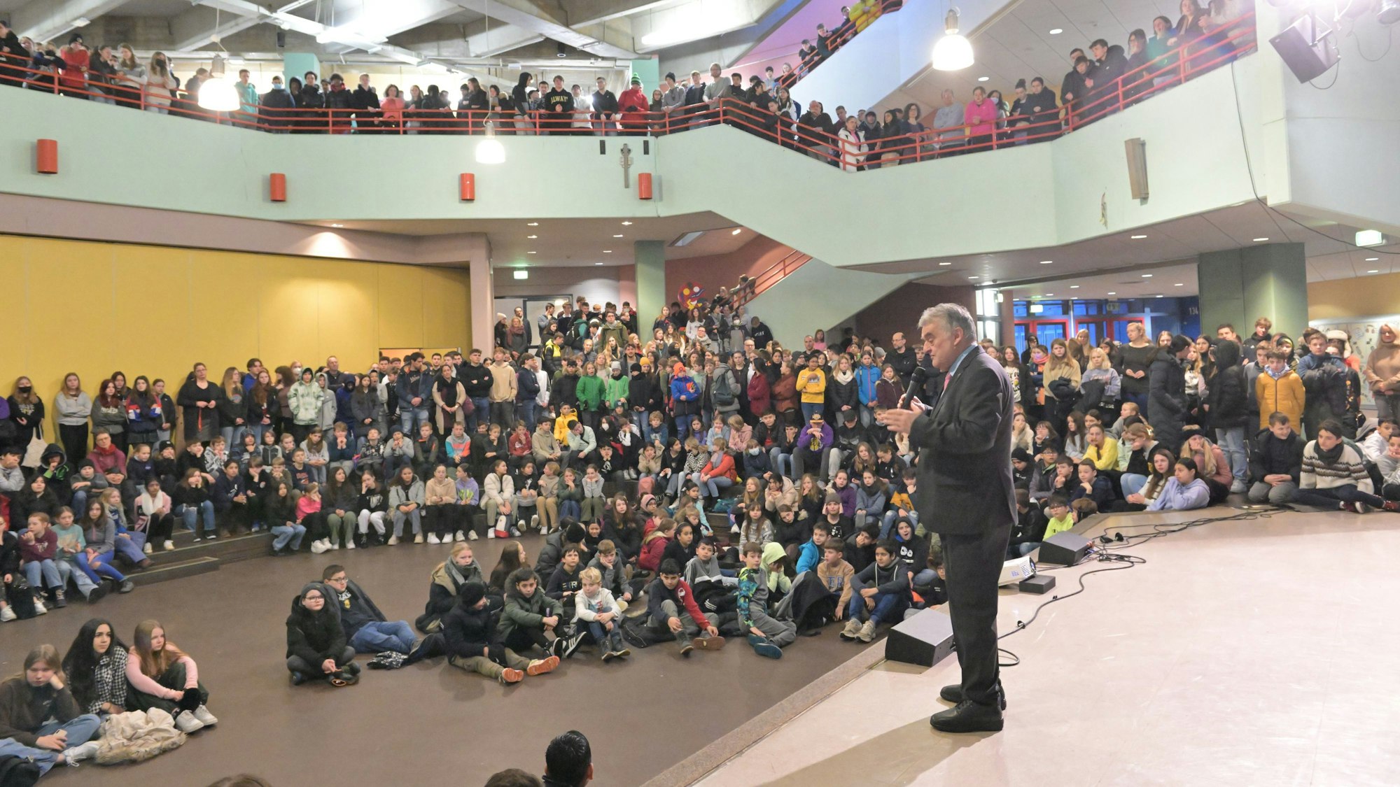 Innenminister Herbert Reul steht auf einer Bühne und spricht zu Schülerinnen und Schüler.