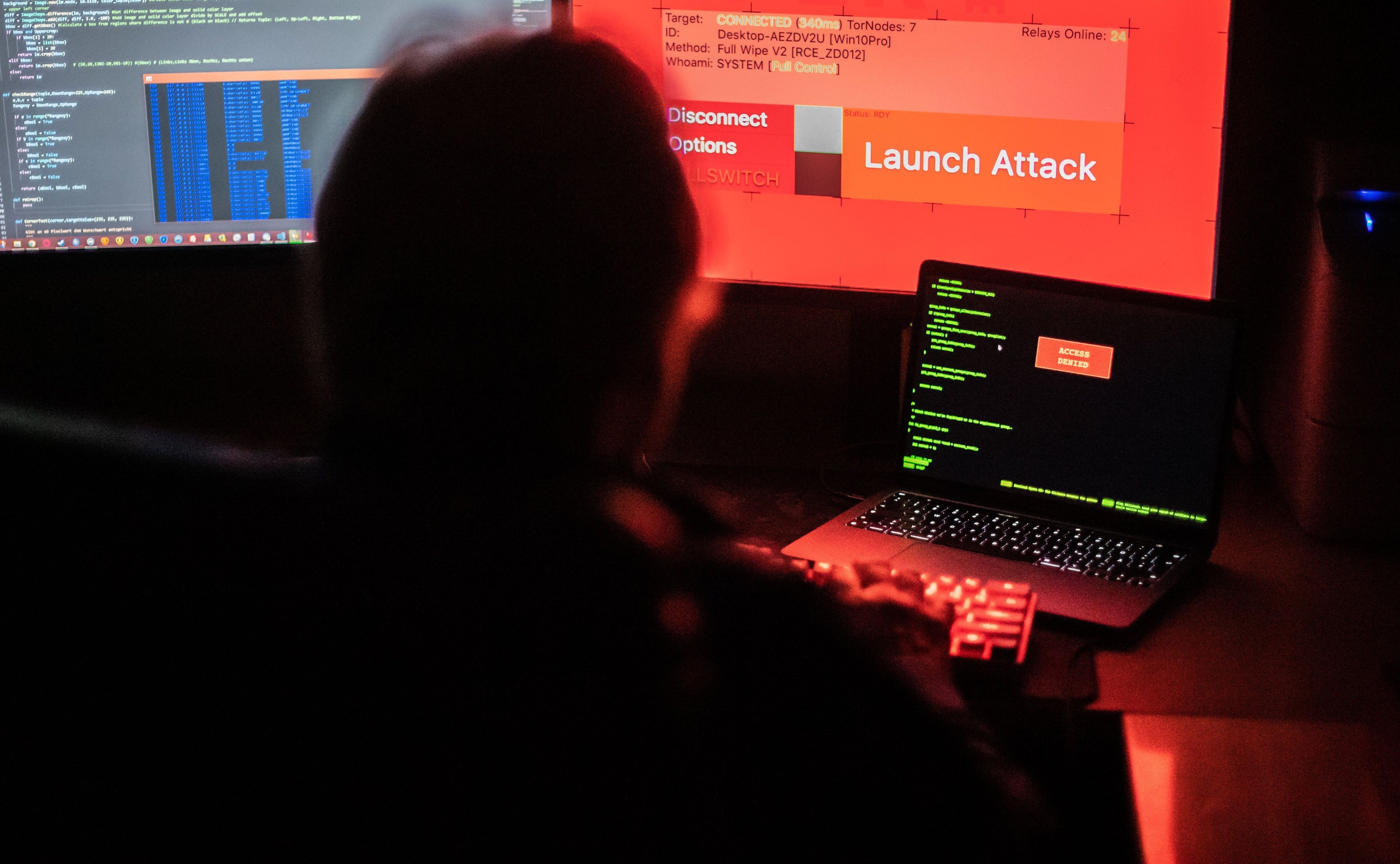 Ein Mann sitzt vor Bildschirmen, die Hacker-Programme und eine fiktive Fernlösch-Software zeigen (Archivbild).