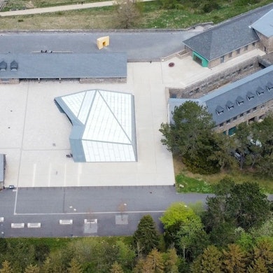 Blick aus der Luft auf das Besucherzentrum im Adlerhof mit der Glaskonstruktion, dessen Dach undicht ist.