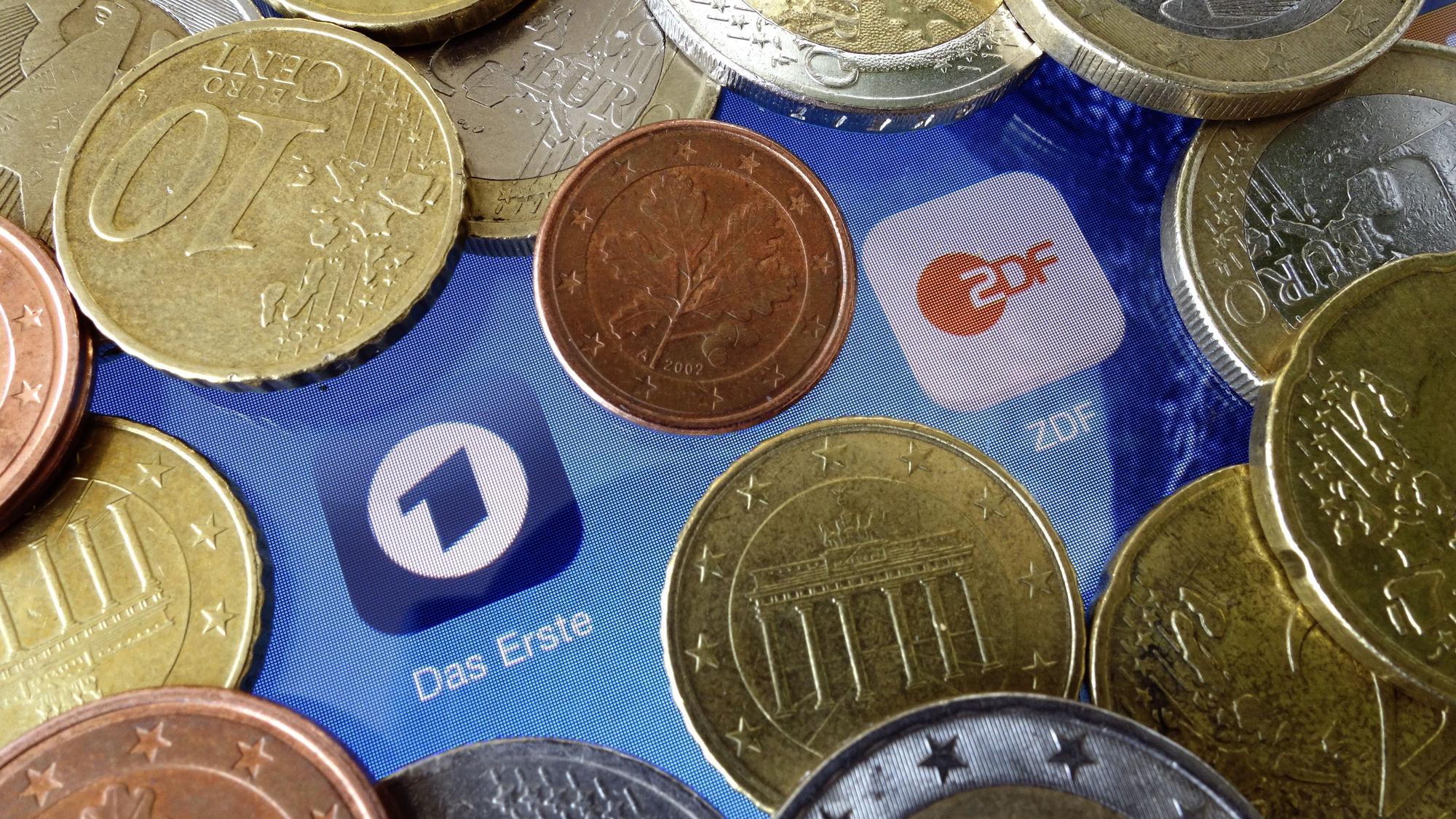Euromünzen liegen neben den Logos der Apps von ARD und ZDF.