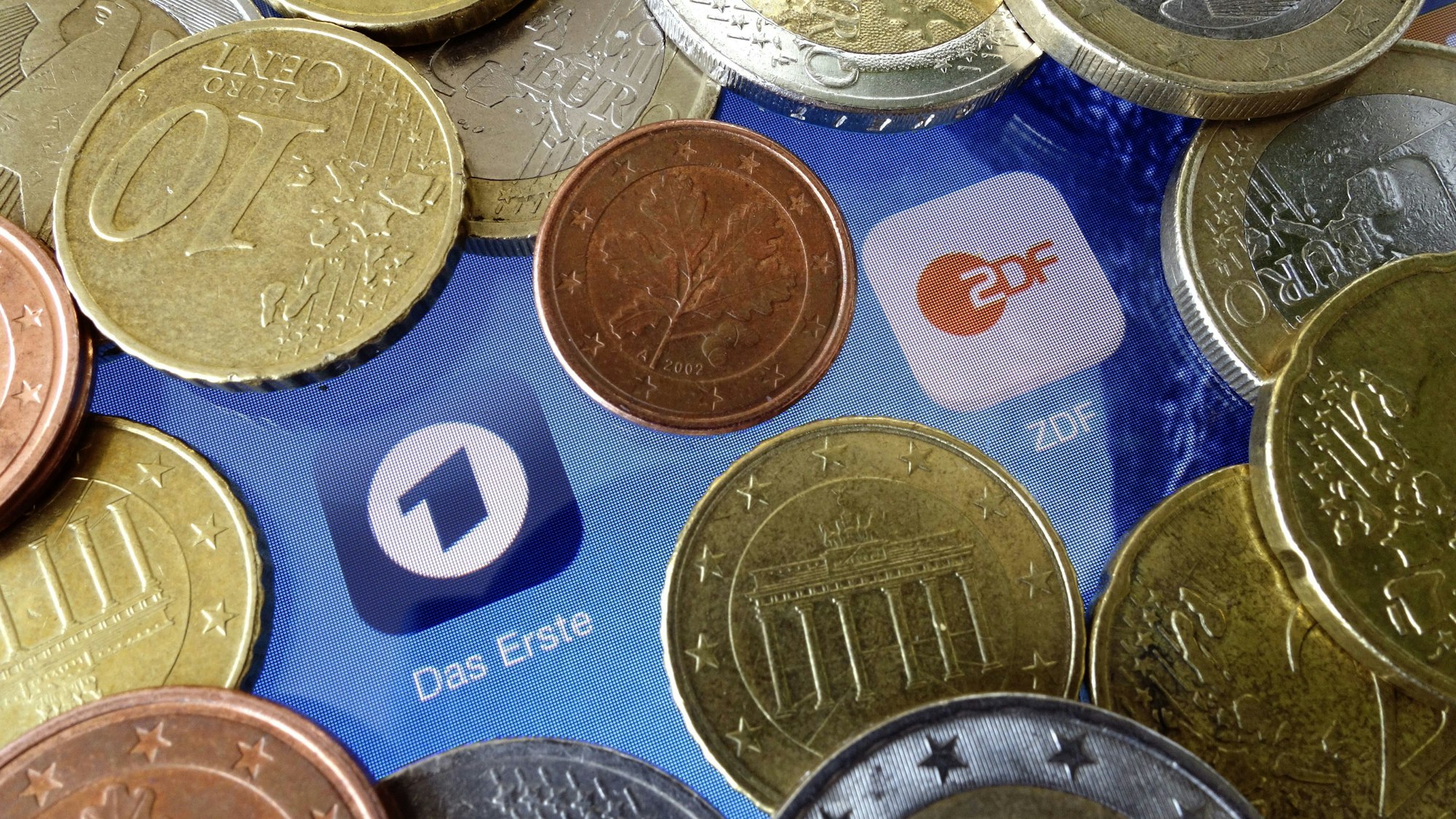 Euromünzen liegen neben den Logos der Apps von ARD und ZDF.