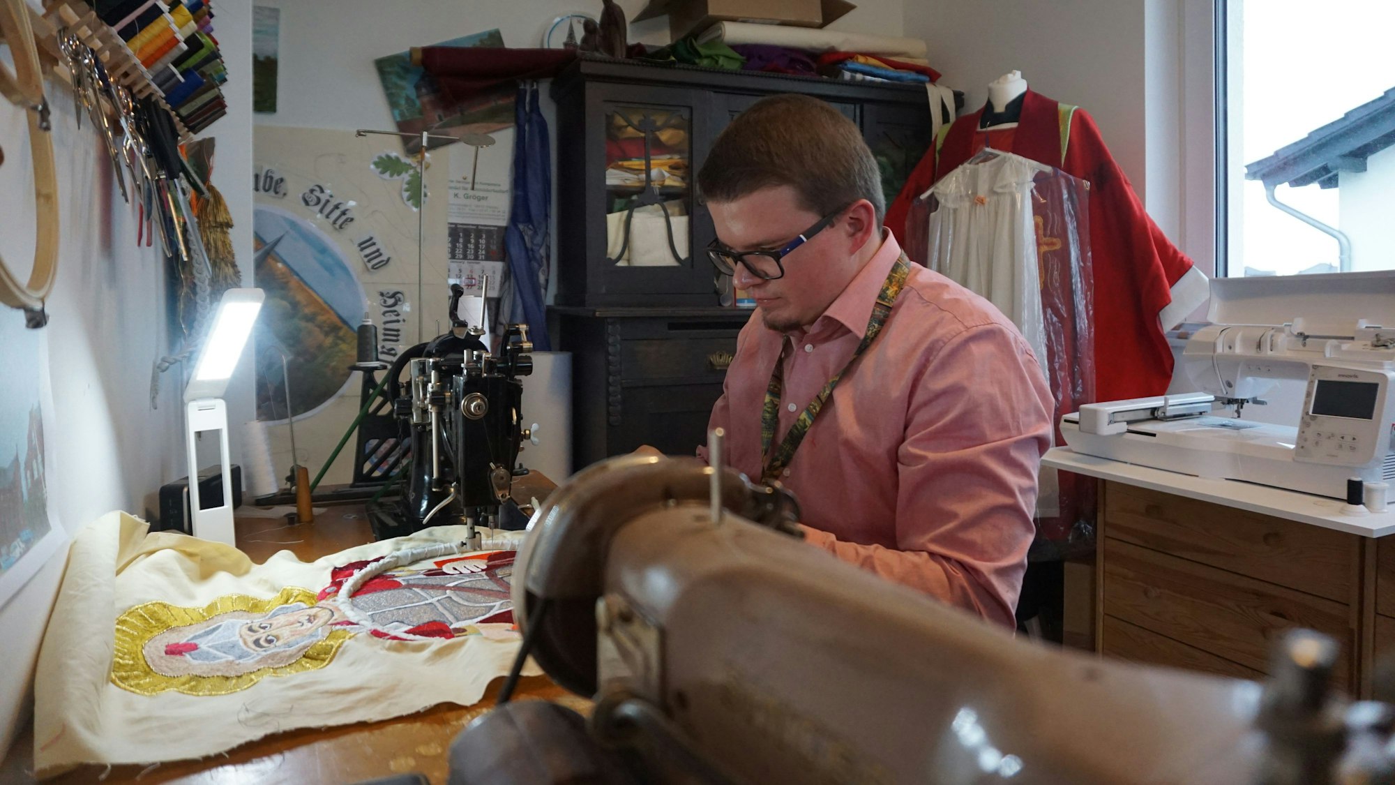 Ein Mann sitzt an einer Nähmschine.