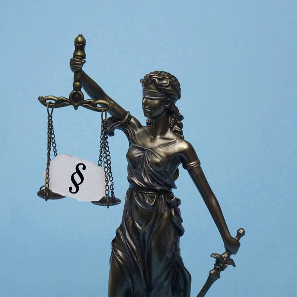 Das Modell der Justitia trägt ein Paragrafensymbol.