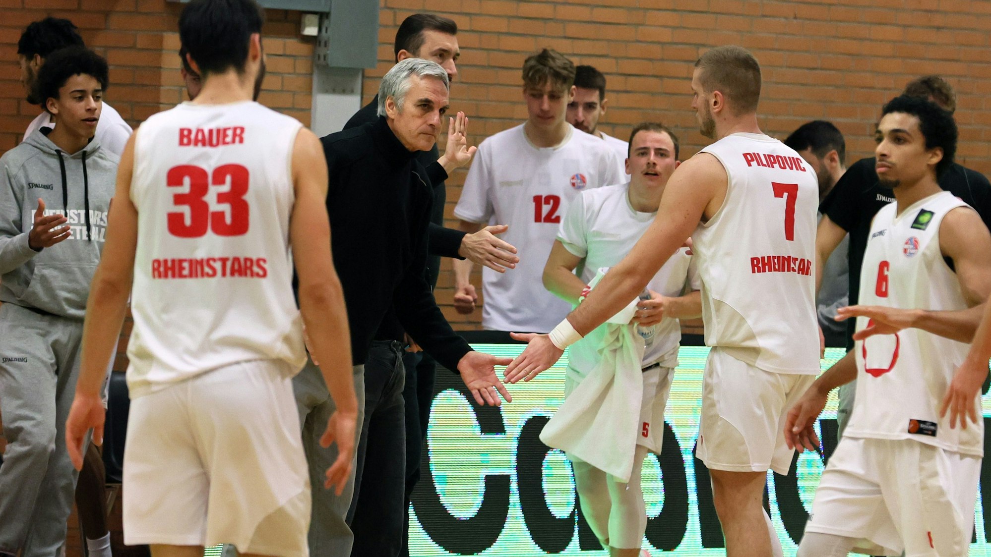 Ein Basketballtrainer versammelt seine Mannschaft zu einer Auszeit um sich.