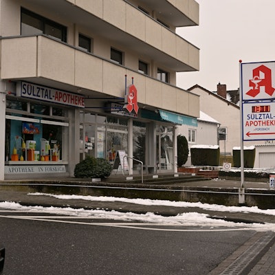Der Parkplatz einer Apotheke ist leer. Nur ein paar Meter weiter hinten ist das Schild der nächsten Apotheke zu sehen.