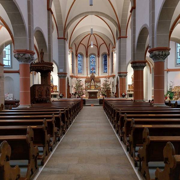 Rechts und links neben einem leeren Gang zum Altar stehen leere Kirchenbänke.