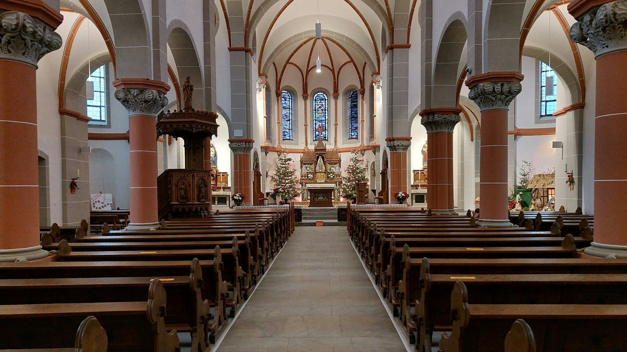 Rechts und links neben einem leeren Gang zum Altar stehen leere Kirchenbänke.