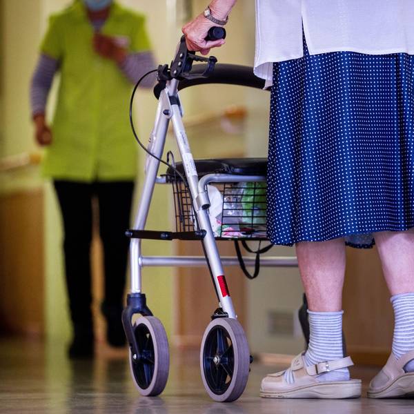 Eine Seniorin geht mit ihrem Rollator über den Gang in einer Pflegeeinrichtung.