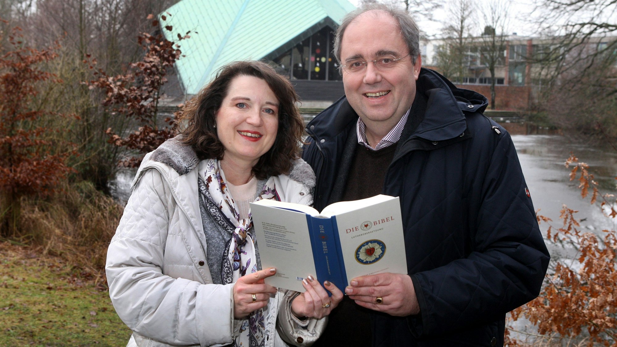 Pfarrersehepaar Birgit und Robert Dwornicki halten eine Bibel hoch.