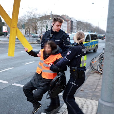 Eine Klima-Aktivistin der „Letzten Generation“ wird von der Straße getragen.