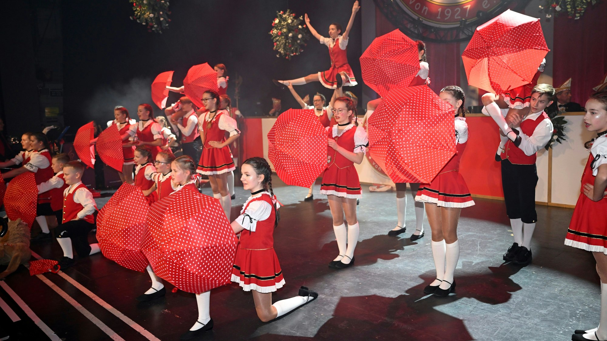 Die Tanzgruppe der Strunde-Pänz steht mit aufgespannten Schirmen auf der Bühne des Bergischen Löwen.