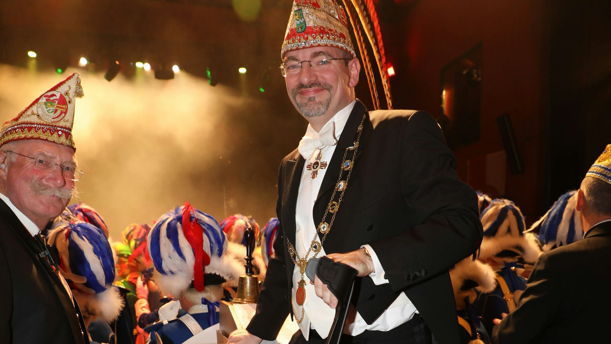 Präsident Alexander Pfister stützt sich auf eine Krücke hinterm Elferratstisch. Im Hintergrund ist der Saal zu sehen.