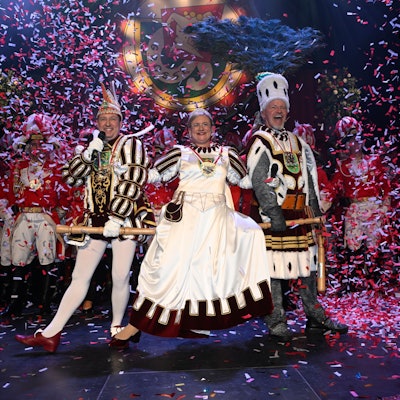 Das Bergisch Gladbacher Dreigestirn steht im Konfettiregen auf der Bühne.