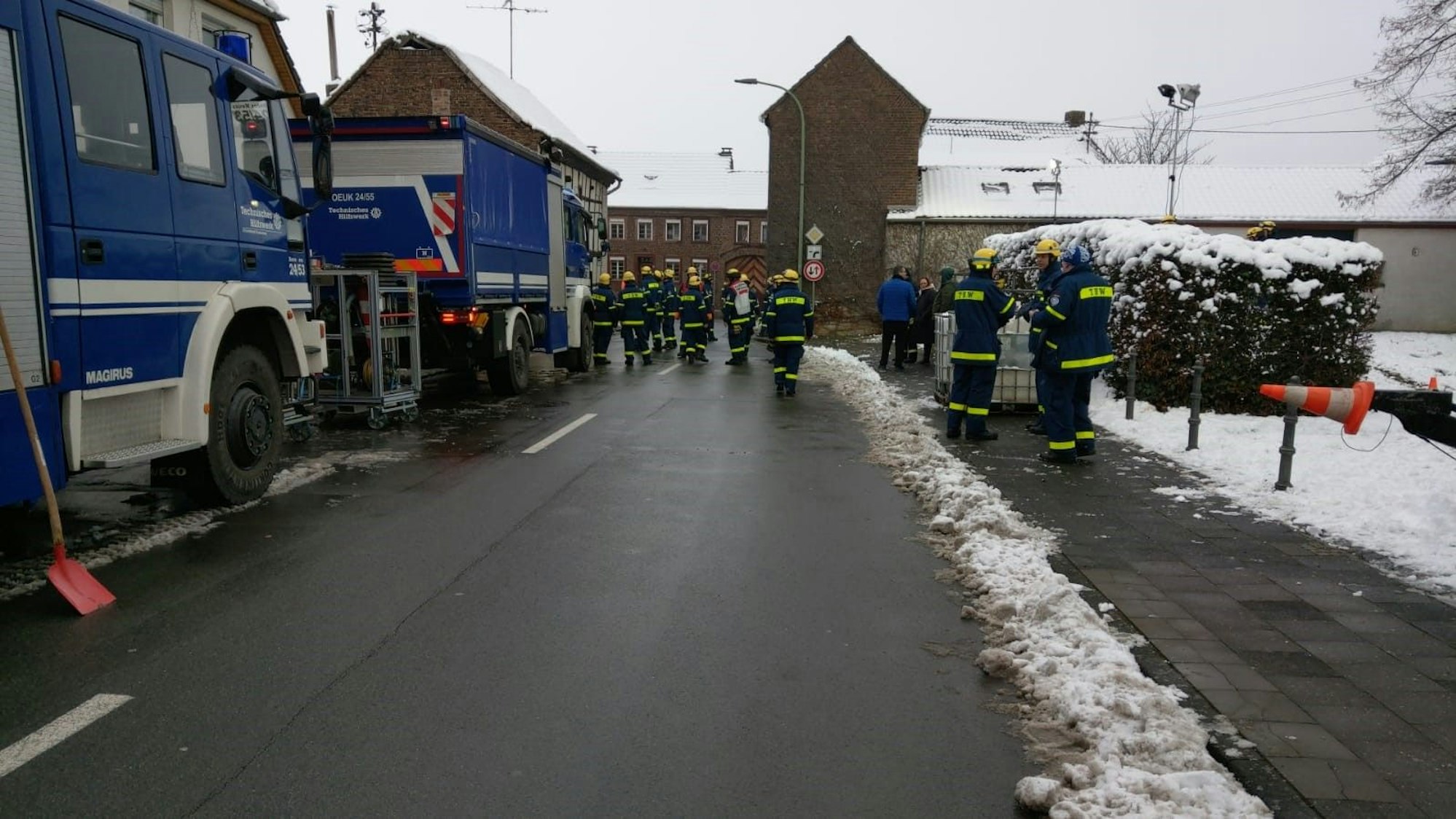 Einsatzkräfte des THW stehen auf der Straße und bereiten ihren Einsatz vor.