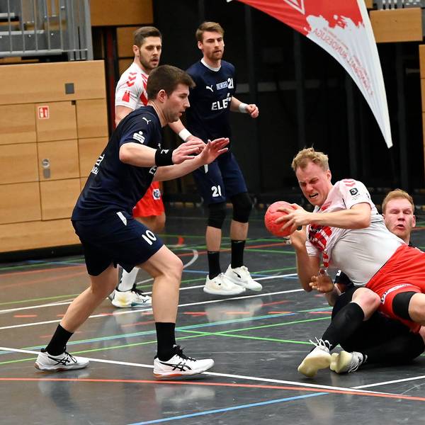 Ein Handballer wird von seinem Gegenspieler auf den Boden gezogen.