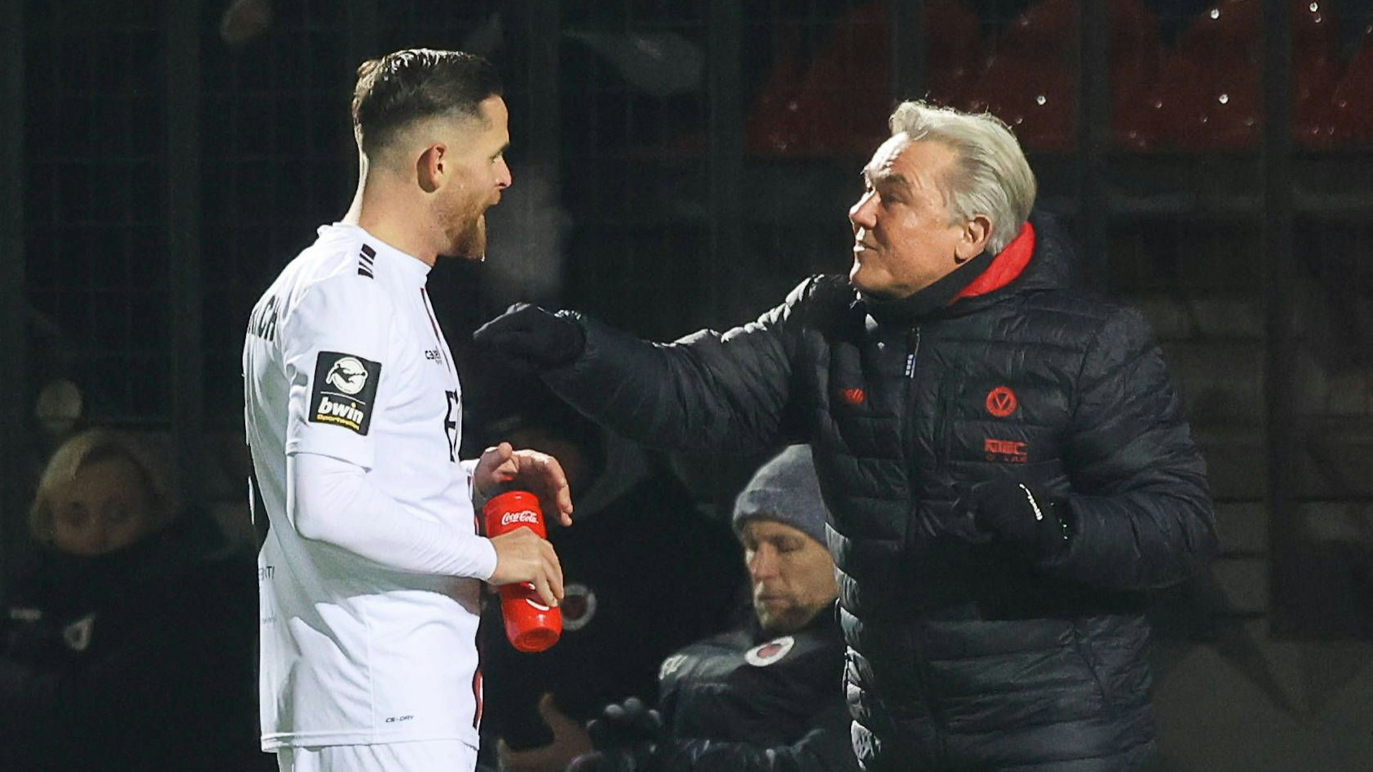 Ein Fußballtrainer redet am Spielfeldrand auf seinen Spieler ein.