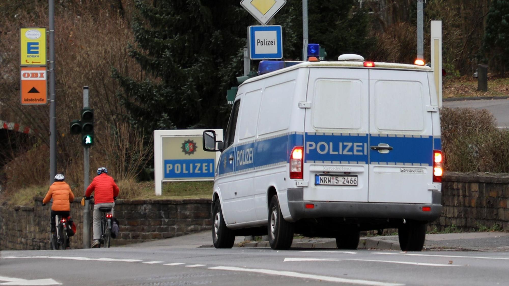 Ein Polizeifahrzeug steht in Bergisch Gladbach an einer Einmündung, an der ein Polizei-Schild steht.