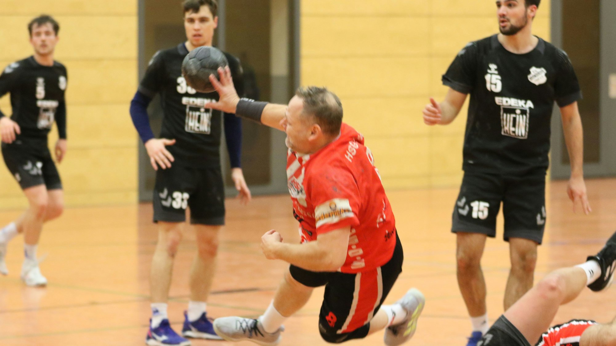 Stefan Tuitje, Trainer der HSG Euskirchen, ist beim Wurf von gegnerischen Spielern umring.