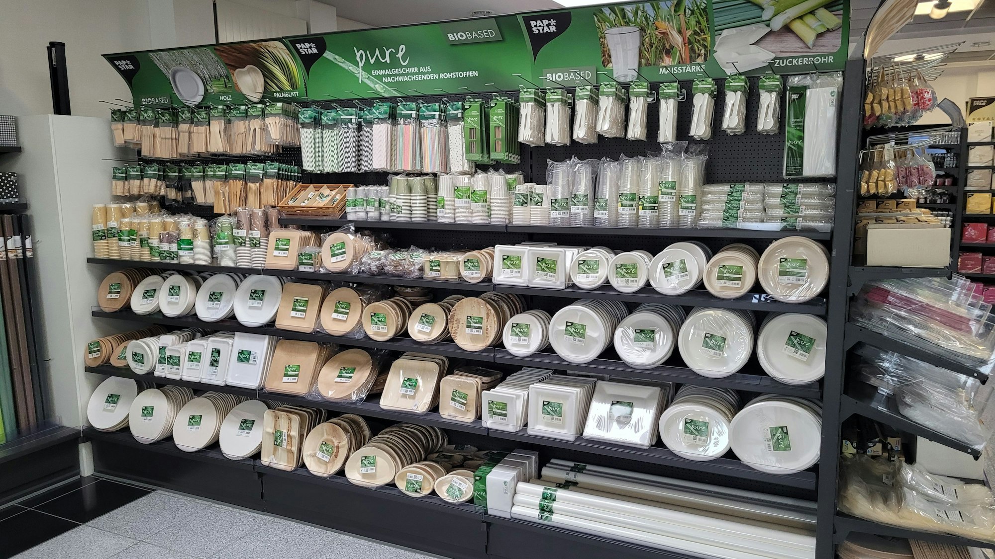 In einem Regal ist Einmalgeschirr aus nachwachsenden Rohstoffen aufgereiht.