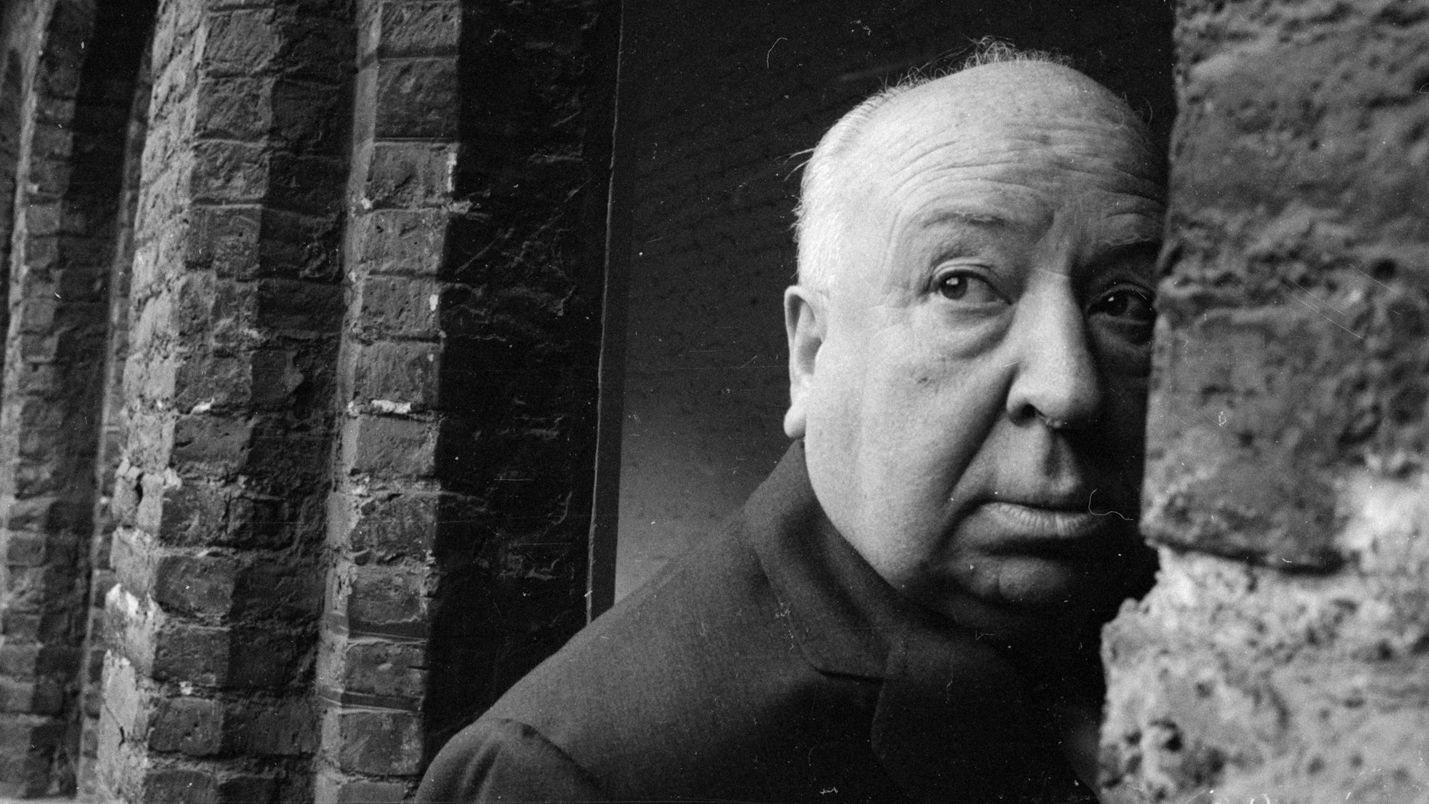 Alfred Hitchcock schaut an einer Wand vorbei.