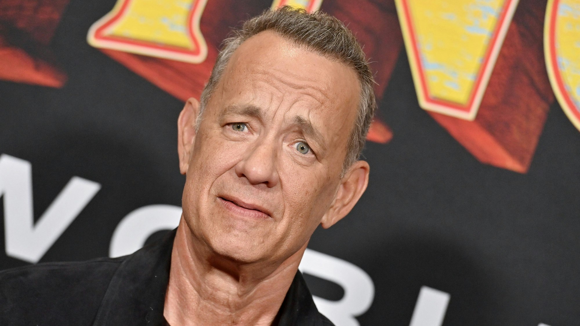 Tom Hanks vor einem Plakat von „Pinocchio“.