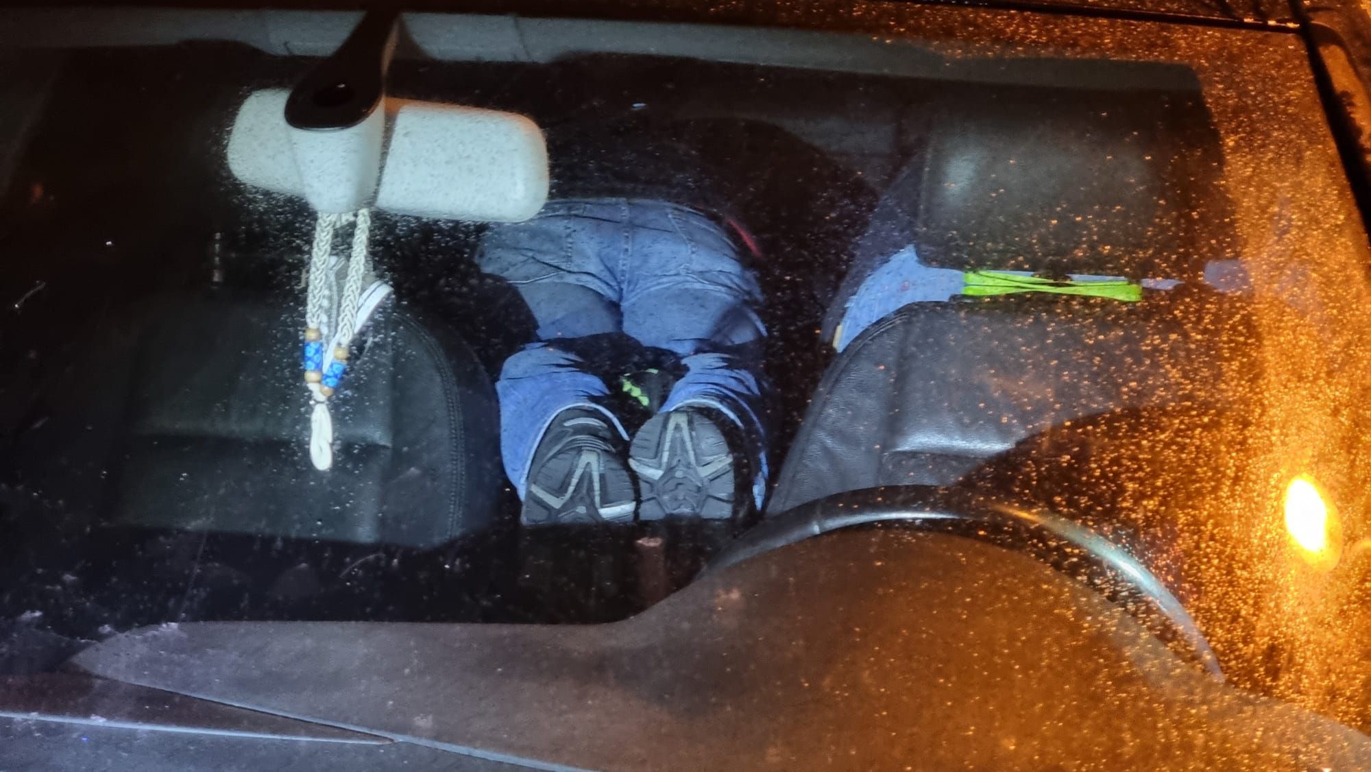 Zwei Männer liegen auf dem Bauch im Auto.