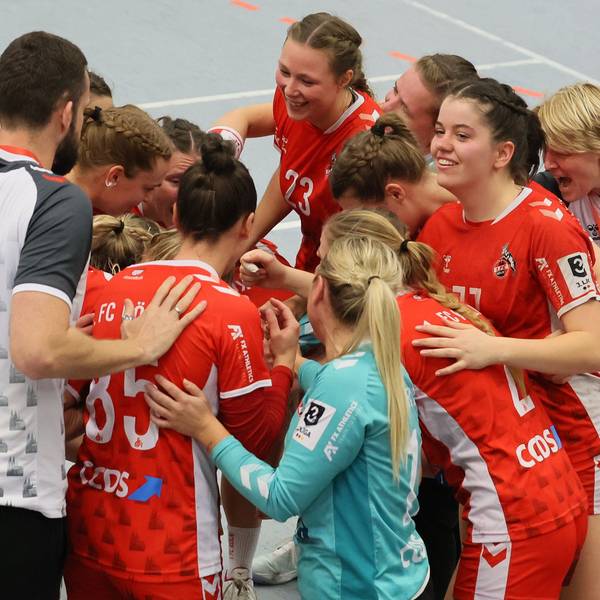 Ein Frauen-Handballteam steht im Kreis zusammen und freut sich über einen Sieg.