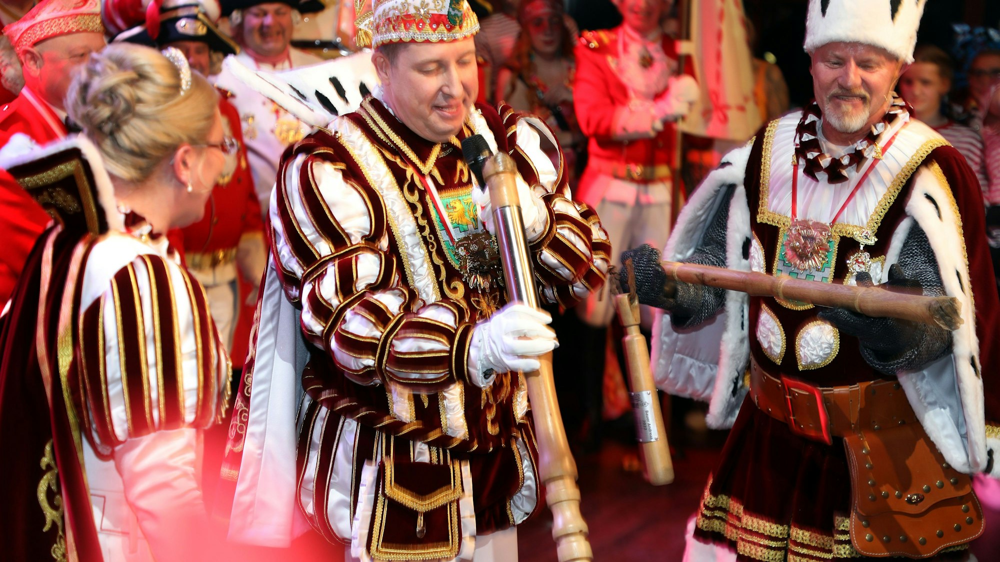 Prinz Frank III. und Bauer Andreas halten jeweils einen Teil des zerbrochenen Dreschflegels in den Händen.Jungfrau Melanie lacht.