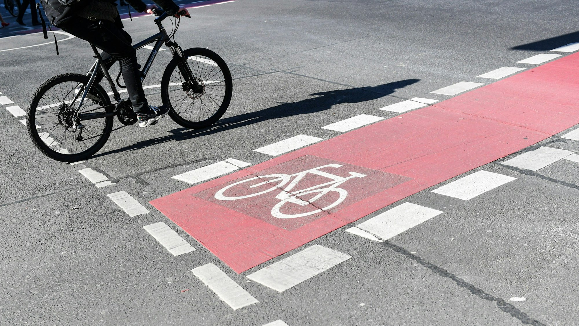 Ein Radfahrer fährt auf einer Straße neben einem rot markierten Radweg.