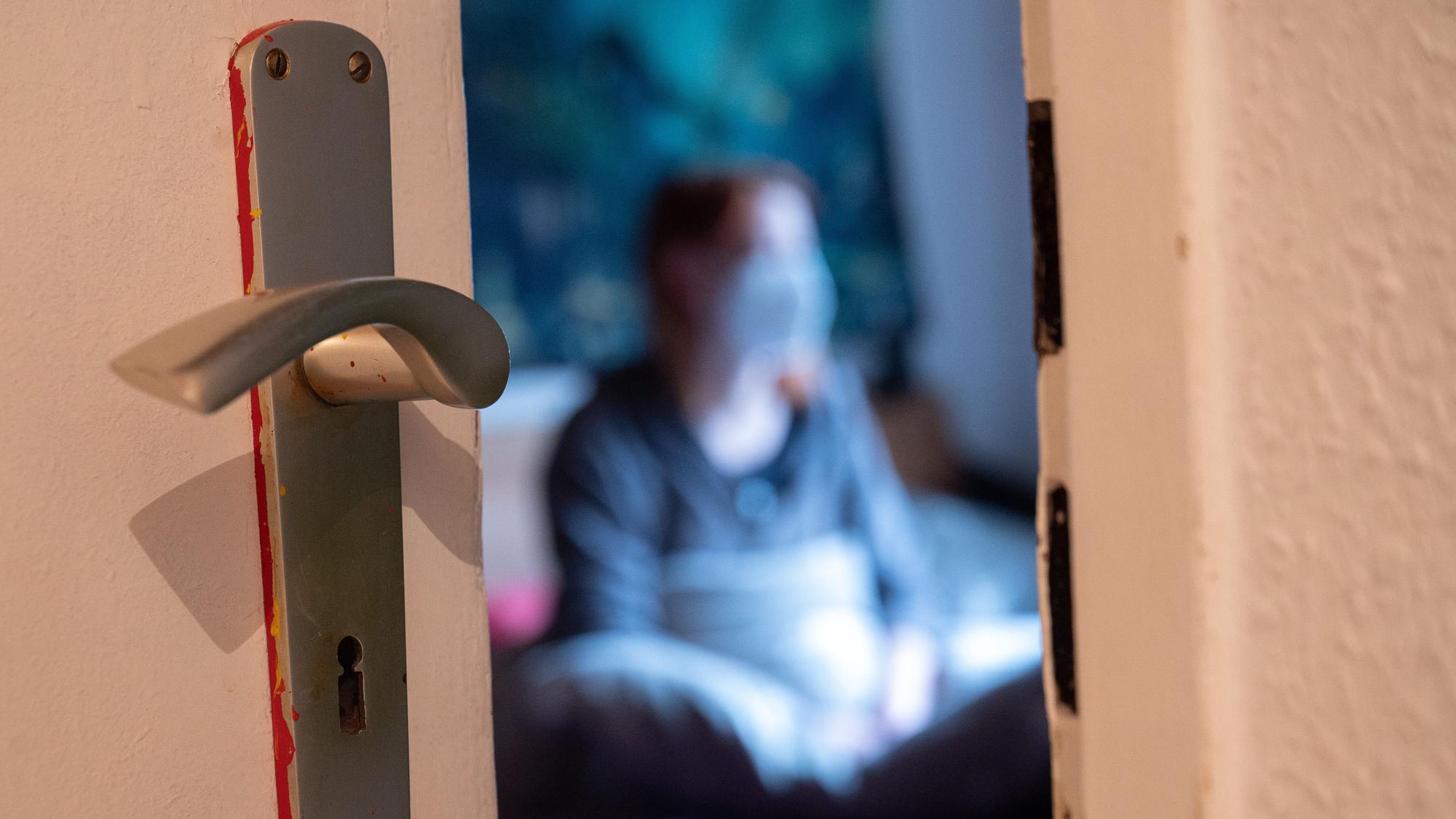 Eine Frau sitzt während der Isolation nach einem positiven Corona-PCR-Test auf ihrem Bett.